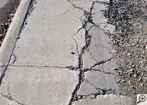 A severely damaged, sinking sidewalk with washed out sand underneath in Camp Hill.