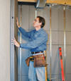 Insulated basement wall panels being placed against a concrete foundation wall in Johnstown